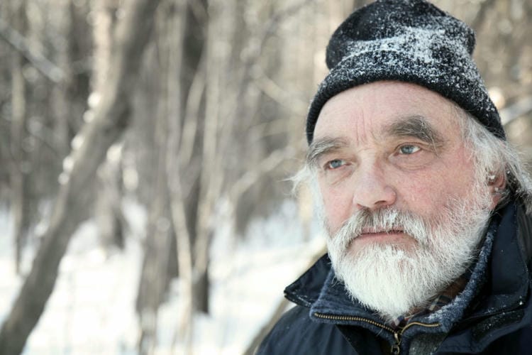 portrait of a senior adult with gray beard in winter forest